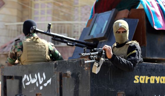 Members of Peace Brigades, a Shiite militia group loyal to Shiite cleric Muqtada al-Sadr, heading to Tikrit, where Iraqi troops backed by Shiite fighters and Iranian advisers are fighting extremists, sit with their weapons in an armored vehicle as they leave Baghdad, Iraq, Sunday, March 15, 2015. Dozens of fighters with the militia loyal to the radical Shiite cleric left Iraq's capital Sunday to take part in an offensive to capture Tikrit from the Islamic State group. (AP Photo/Karim Kadim)
