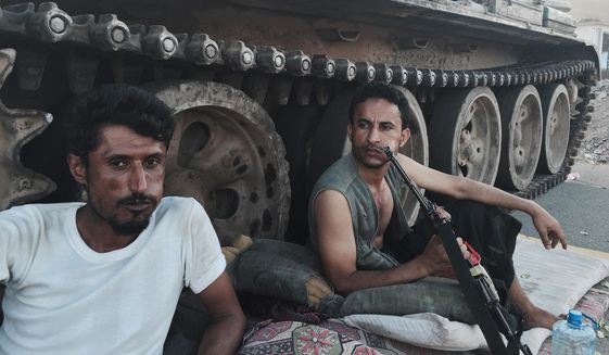 Members of a militia group loyal to Yemen&#39;s President Abed Rabbo Mansour Hadi, known as the Popular Committees, chew qat as they sit next to their tank, guarding a major intersection in Aden, Yemen, in this March 21, 2015, file photo. Once hailed by President Barack Obama as a model for fighting extremism, the U.S. counterterrorism strategy in Yemen has all but collapsed as the country descends into chaos, according to U.S. and Yemeni officials. (AP Photo/Hamza Hendawi, File)