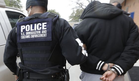 A U.S. Immigration and Customs Enforcement agent escorts a handcuffed illegal immigrant convicted of a felony that was taken into custody during an early morning operation in Dallas on March 6. (Associated Press)