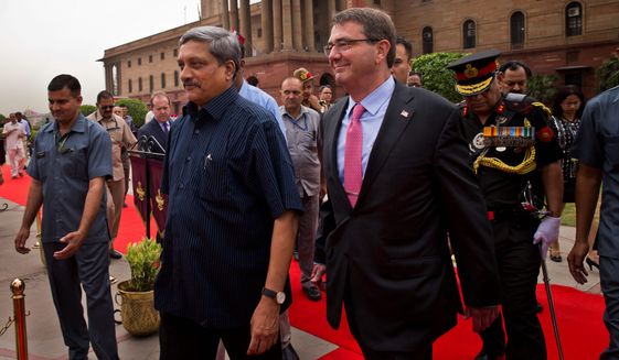 Defense Secretary Ashton Carter walks with Indian Defense Minister Manohar Parrikar after receiving a ceremonial welcome in New Delhi. Mr. Carter signed a 10-year agreement with India seen by some as a move to counter China's growing influence. (Associated Press)