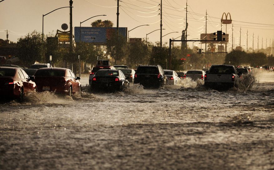 Cars drive through flood water on a street Monday, July 6, 2015, in Las Vegas. Heavy rain throughout the area prompted the National Weather Service to issue a flash flood warning for parts of Las Vegas. (AP Photo/John Locher)