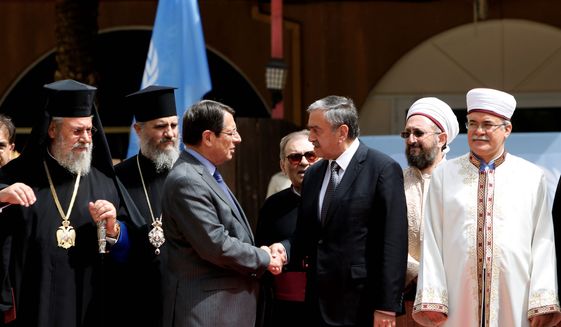 Cyprus' president Nicos Anastasiades and Turkish Cypriot leader Mustafa Akinci shake hands after a meeting at U.N. buffer zone at Ledra Palace Hotel in divided capital Nicosia, Cyprus in September. The heads of Cyprus' Christian and Muslim communities are meeting with the ethnically divided island's rival leaders to lend their support to ongoing reunification talks. (Associated Press)