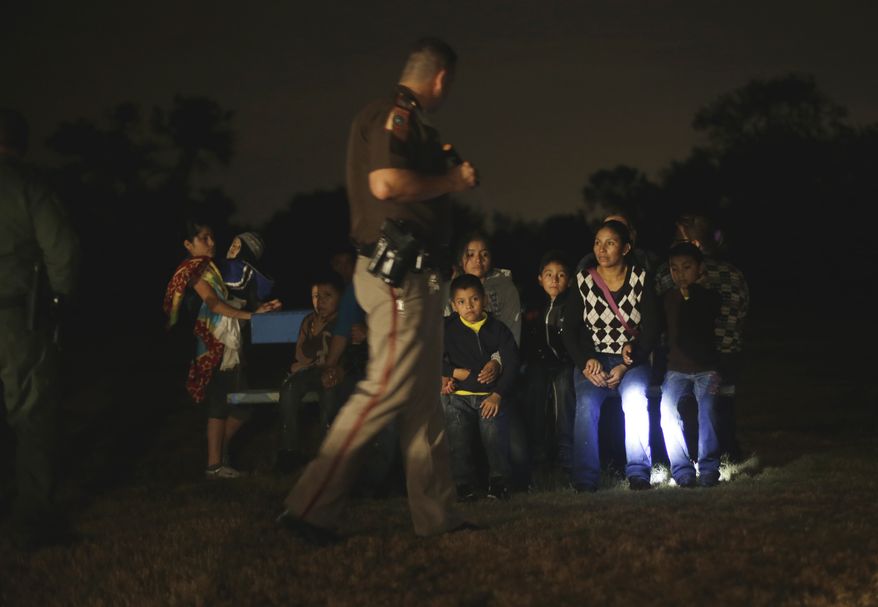 A group of immigrants from Honduras and El Salvador who crossed the U.S.-Mexico border illegally are stopped on June 25, 2014, in Granjeno, Texas. (Associated Press) **FILE**