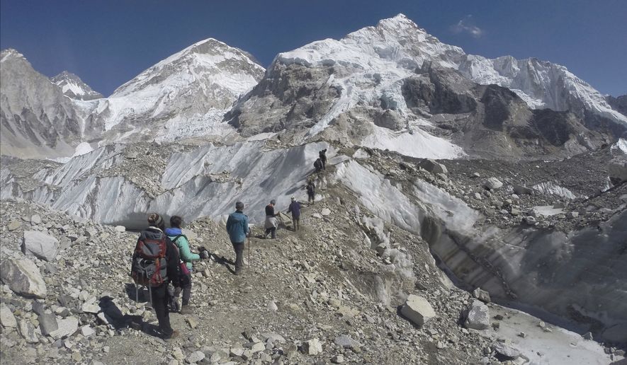 In this Monday, Feb. 22, 2016, file photo, international trekkers pass through a glacier at the Mount Everest base camp, Nepal. An Indian climber has died while being helped down Mount Everest, just hours after a Dutch and an Australian climber died near the peak. (AP Photo/Tashi Sherpa, File)