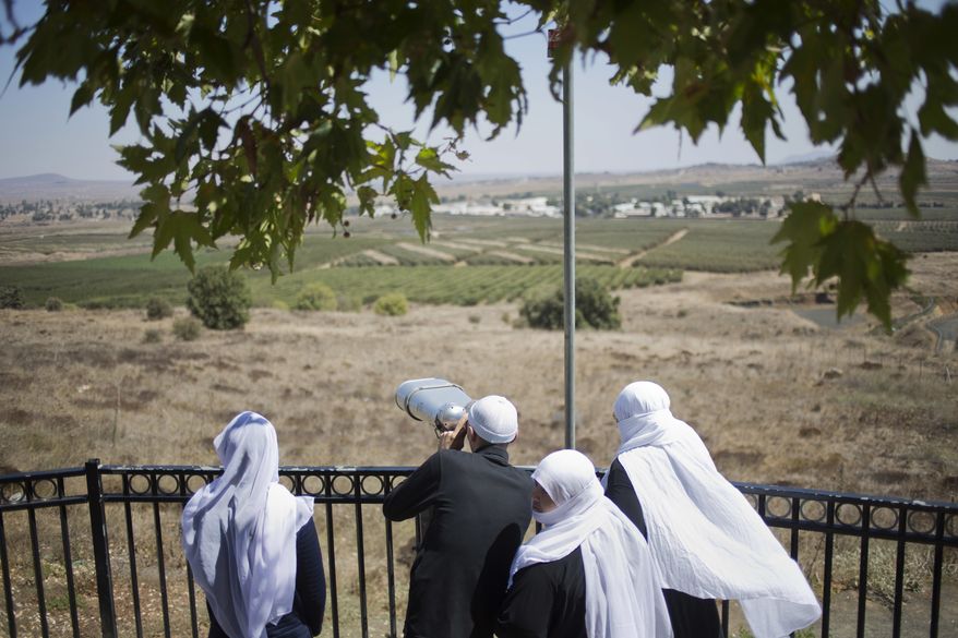 A Druze family, celebrating the Eid al-Adha holiday, look towards Syria's Quneitra province as they visit an observation point in the Israeli-controlled Golan Heights, Tuesday, Sept. 13, 2016. Israel is denying Syrian government claims that its forces shot down a warplane and a drone near the Israeli-controlled part of the Golan Heights. Israeli warplanes have conducted several air raids on Syrian army positions over the past weeks after stray shells hit the Israeli-occupied area. (AP Photo/Ariel Schalit)