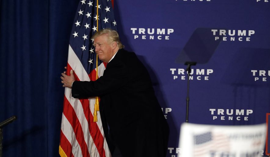 Republican presidential candidate Donald Trump hugs an American flag after speaking at a rally Monday, Nov. 7, 2016 in Leesburg, Va. (AP Photo/Alex Brandon)