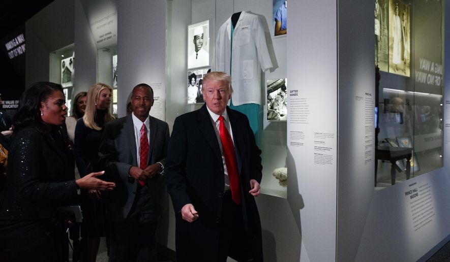 President Donald Trump walks with Housing and Urban Development Secretary-designate Dr. Ben Carson, as they pass a exhibit honoring Carson during a tour of the National Museum of African American History and Culture, Tuesday, Feb. 21, 2017, in Washington. (AP Photo/Evan Vucci)