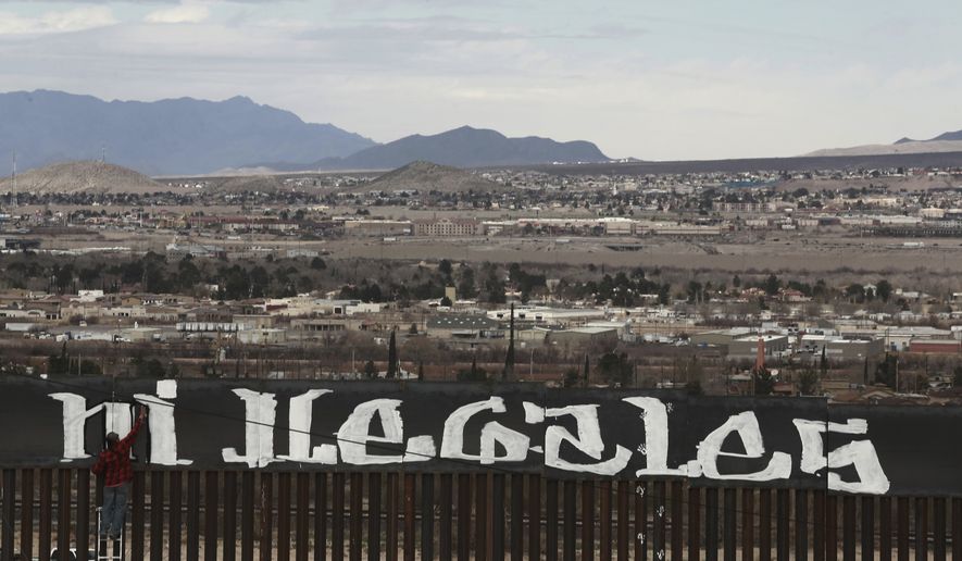 Sunland Park, New Mexico, is seen over the U.S. border fence as a protestor finishes painting the Spanish slogan &quot;Neither delinquents nor illegals, we are international workers&quot; on the Ciudad Juarez, Mexico side of the fence, Sunday, Feb. 26, 2017. A group of around 30 protestors gathered to paint messages on the border wall on the outskirts of Ciudad Juarez and stage a performance mocking the relationship between Presidents Donald Trump and Enrique Pena Nieto. (AP Photo/Christian Torres)