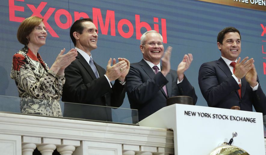 In this Wednesday, March 1, 2017, file photo, Exxon Mobil Corporation Chairman & CEO Darren Woods, third from left, joins the applause during opening bell ceremonies at the New York Stock Exchange. Woods succeeded Rex Tillerson, following Tillerson's nomination by President Donald Trump to be the next United States Secretary of State. Woods is a veteran of the more cautious refining side of the oil business who is likely to focus relentlessly on controlling costs. (AP Photo/Richard Drew, File)