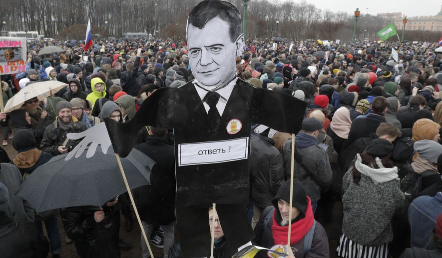 Protesters hold a cardboard cutout poster depicting Russian Prime Minister Dmitry Medvedev at Marsivo Field in St.Petersburg, Russia, Sunday, March 26, 2017. Thousands of people crowded in St.Petersburg on Sunday for an unsanctioned protest against the Russian government, the biggest gathering in a wave of nationwide protests that were the most extensive show of defiance in years. (AP Photo/Dmitri Lovetsky)