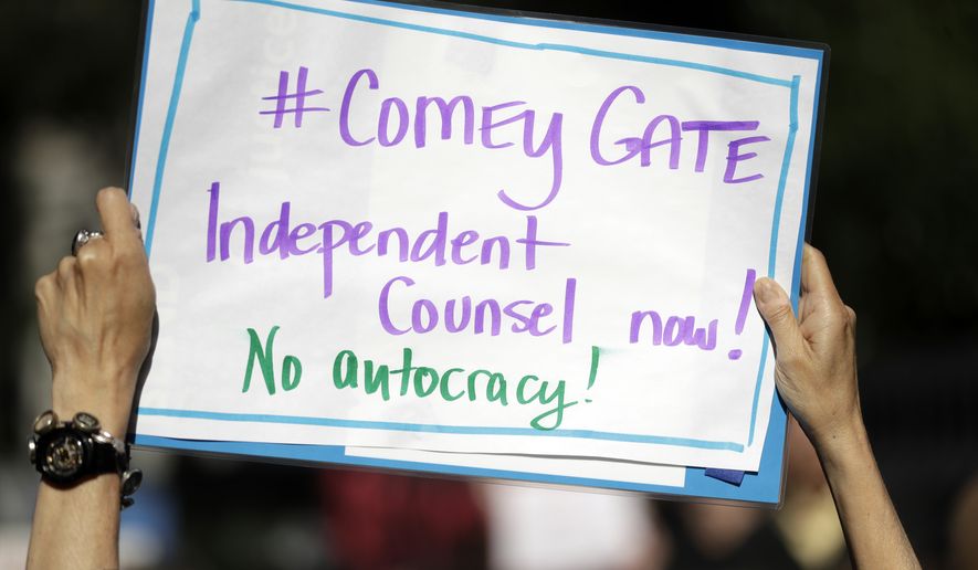 A protester waves a sign outside of the offices of Sen. Dianne Feinstein, D-Calif., Wednesday, May 10, 2017, in San Francisco. Dozens of protesters chanted slogans outside of Feinstein&#39;s office in protest of President Donald Trump&#39;s firing of FBI director James Comey. (AP Photo/Marcio Jose Sanchez)