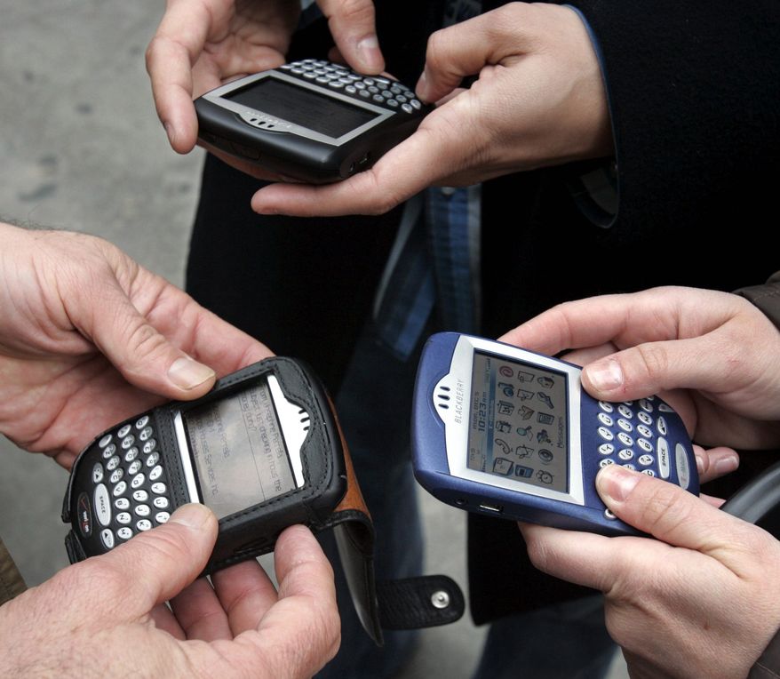 **FILE** Three people use BlackBerry devices in New York&#39;s Times Square on Dec. 5, 2005. (Associated Press) 