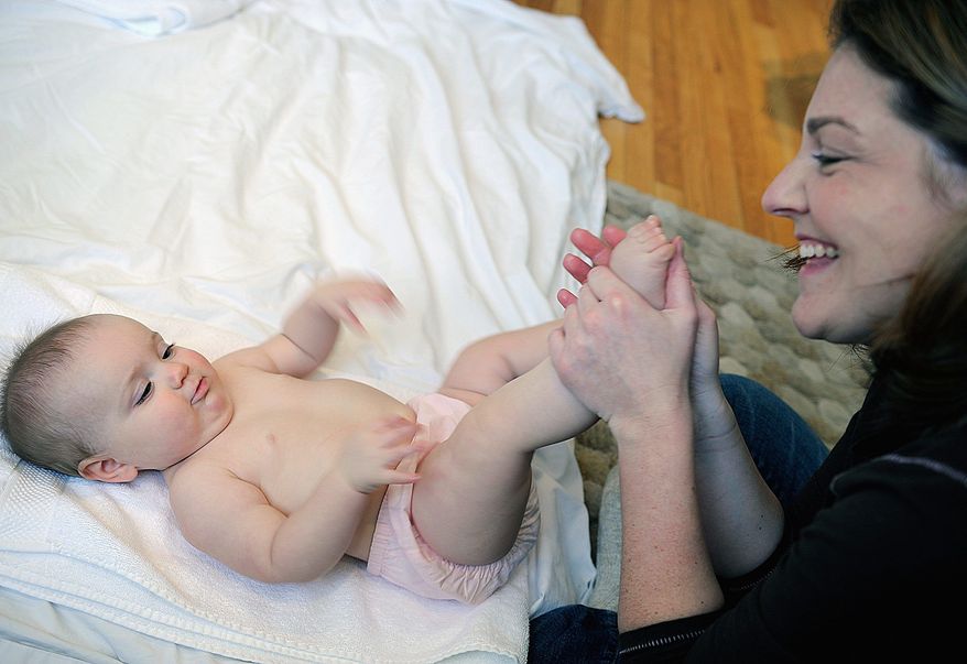 *FILE* In this 2008 photo, Wendy Dutton of Arlington massages her 8-month-old daughter, Maya, earlier this month during an infant massage class at Hela Spa in Georgetown. (Barbara L. Salisbury/The Washington Times)