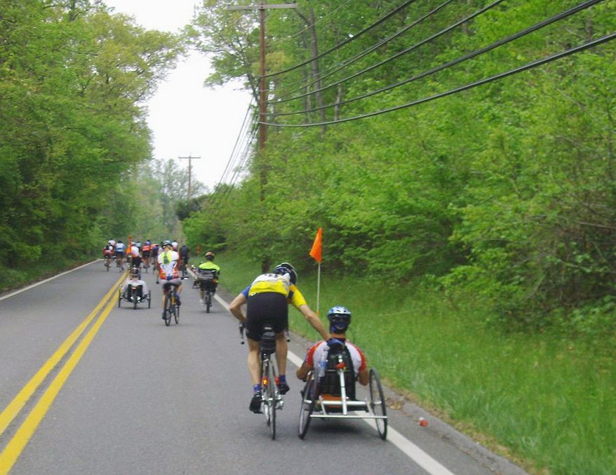 ** FILE ** Clint Provenza of Severna Park, Md., assists a participant up a hill during the Wounded Warrior Project Soldiers Ride in Annapolis. Below, eager riders line up at the starting line. (Tom Galligan/The Washington Times)