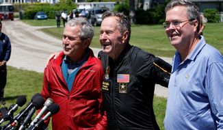 **FILE** Former President George H.W. Bush (center) is joined by his sons, former President George W. Bush and former Florida Gov. Jeb Bush, as he recounts Friday&#39;s birthday jump with the Army Golden Knights parachute team to celebrate his 85th birthday. (Associated Press)
