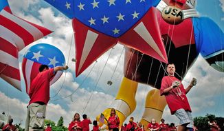 A family from Long Island, N.Y., holds onto a flag-themed balloon as the foursome prepares to march in the National Independence Day Parade on Constitution Avenue in Northwest Saturday. (Allison Shelley/Washington Times/File)