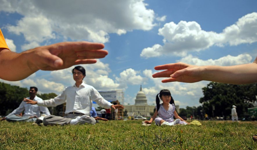 Joel Ng, 5, joins her dad, Ulane Eng (second from left), for meditation Sunday on the Mall as Falun Gong practitioners and their supporters mark the 10th anniversary of a Chinese crackdown on the spiritual movement. It has gained millions of followers since its 1992. founding. (By Astrid Riecken/The Washington Times/File)
