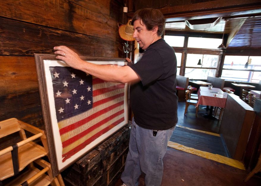 ** FILE ** Silver Spur Saloon proprietor Marc Peagler displays an early 1800s 13-star U.S. flag at his bar in Cave Creek, Ariz., on Friday, June 26, 2009. An Arizona House committee has made dramatic changes to a Senate-passed bill allowing people with concealed weapons permits to carry their firearms into businesses that serve alcohol. Mr. Peagler supports the measure. (AP Photo/Aaron J. Latham)