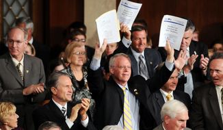 ** FILE ** Rep. Paul Broun, R-Ga., holds up the Republicans version of a health care reform bill, standing with other republicans.  (Allison Shelley / The Washington Times)