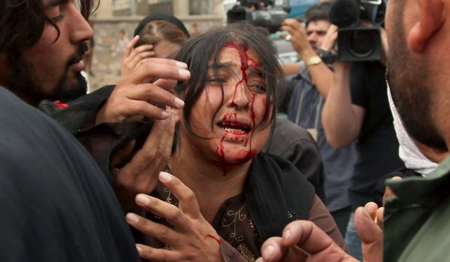 An Afghan woman injured in a Taliban bombing cries for help near the site where a suicide bomber attacked an Italian military convoy on a road in Kabul in this September 2009 photo. (Associated Press)