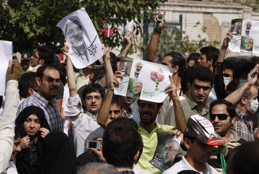 Iranian opposition supporters attend a protest, as they hold pictures of opposition leader Mir Hossein Mousavi, in Tehran, Iran, Friday, Sept. 18, 2009. Thousands of opposition supporters held protests in competition with government-sponsored mass rallies to mark an annual anti-Israel commemoration, the Quds Day that reflects the Persian nation's sympathy with the Palestinians. (AP Photo/Vahid Salemi)