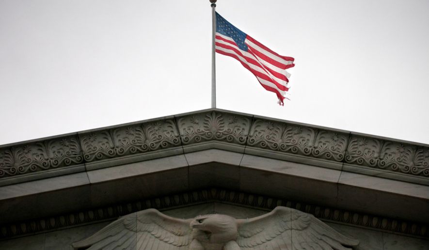 A tattered flag flies over the Rayburn House office building.   (Allison Shelley / The Washington Times)