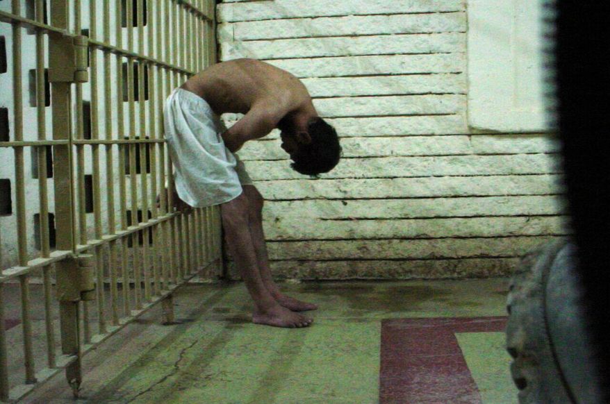 **FILE** This 2003 photo obtained by the Associated Press shows a detainee bent over with his hands on the bars of a prison cell at the Abu Ghraib prison in Baghdad, Iraq. (AP Photo)