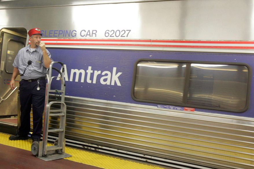 **FILE** A Red Cap stands next to an Amtrak train waiting for passengers at a platform at New York's Penn Station in 2005. (Associated Press)
