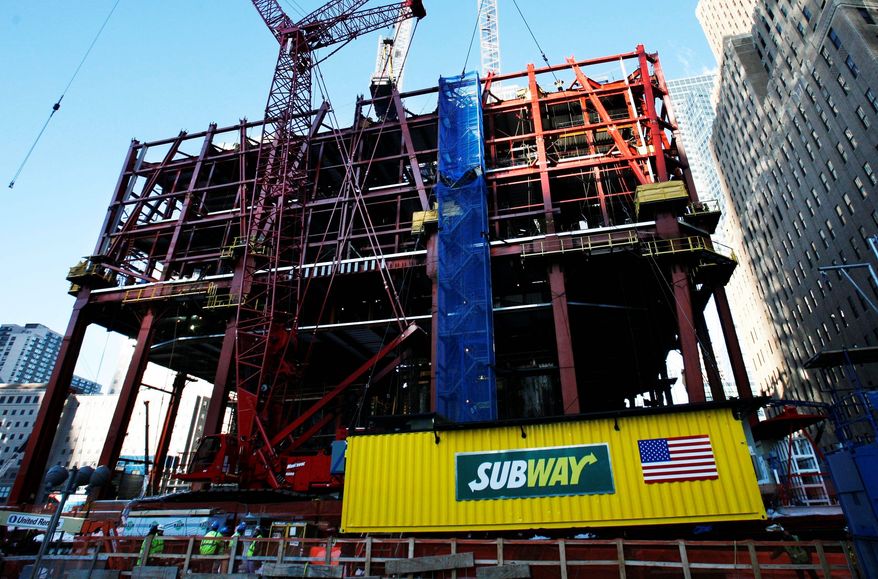 ** FILE ** A Subway sandwich shop is hoisted by crane onto the rising steel frame of One World Trade Center in New York in 2009. The concession trailer fed workers as they built the 105-floor building. (Associated Press)