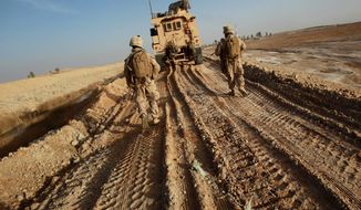 U.S. Marines walk on tracks of a vehicle to avoid improvised explosive devices (IEDs) as their platoon clears a route to reach another platoon in Marjah in Afghanistan&#39;s Helmand province in 2010. Marines airdropped into the region came under intense Taliban fire. (Associated Press)