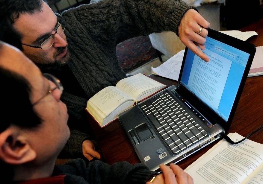 The Rev. William Bulson (left) works with Cher Lor on a translation of the Episcopal Book of Common Prayer into Hmong. Mr. Bulson is a former pastor of Holy Apostles church in St. Paul, Minn., the only Hmong-majority congregation across the entire denomination. He describes the foundational text as "an embodiment of our life and our faith." (Associated Press)