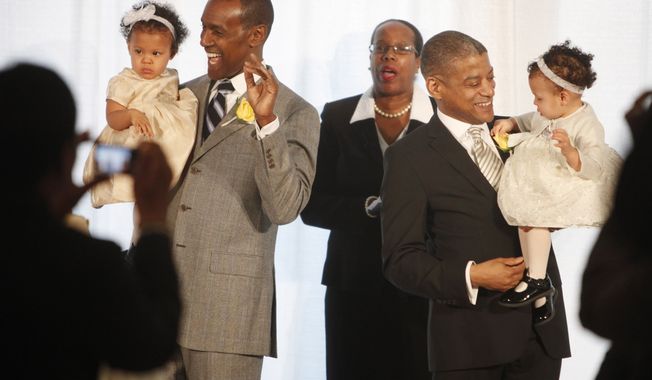 Rocky Galloway (left) and Reginald Stanley hold their twin daughters after the two men were married by the Rev. Sylvia E. Sumter (center) on Tuesday, March 9, 2010, the first day that gay marriage was legal in Washington. (AP Photo/Jacquelyn Martin)
