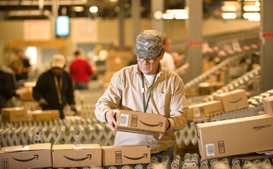 **FILE** An Amazon.com employee grabs boxes off the conveyor belt for shipment at a Fernley, Nev., warehouse. (Associated Press)