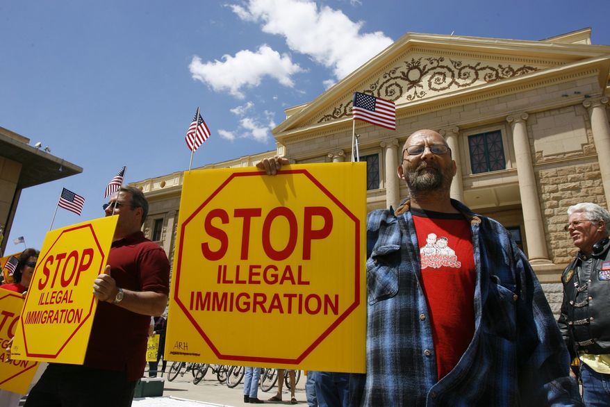 **FILE** Ernie Getford holds a sign in support of the controversial SB1070 illegal immigration enforcement bill during a rally at the state Capitol in Phoenix on April 23, 2010. (Associated Press)