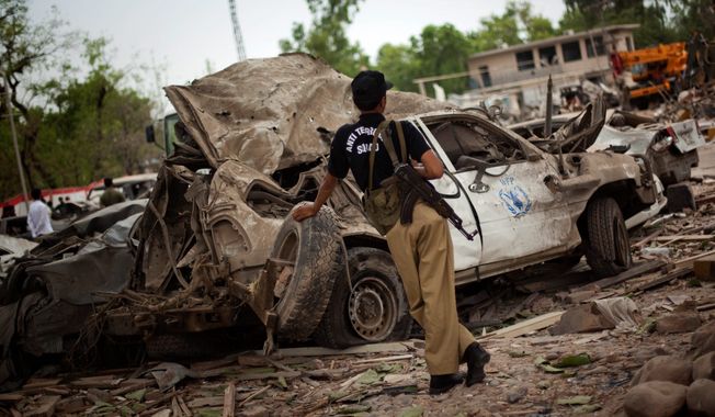 **FILE** A Pakistani police officer guards a U.N. car destroyed in June 2009 by suicide bomber at the Peshawar Pearl Continental Hotel. An increase in terrorist attacks in Pakistan and Afghanistan triggered a spike in the number of civilians killed or wounded in 2009, pushing South Asia past the Middle East as the top terror region in the world, according to new figures compiled by a U.S. intelligence agency. (Associated Press)