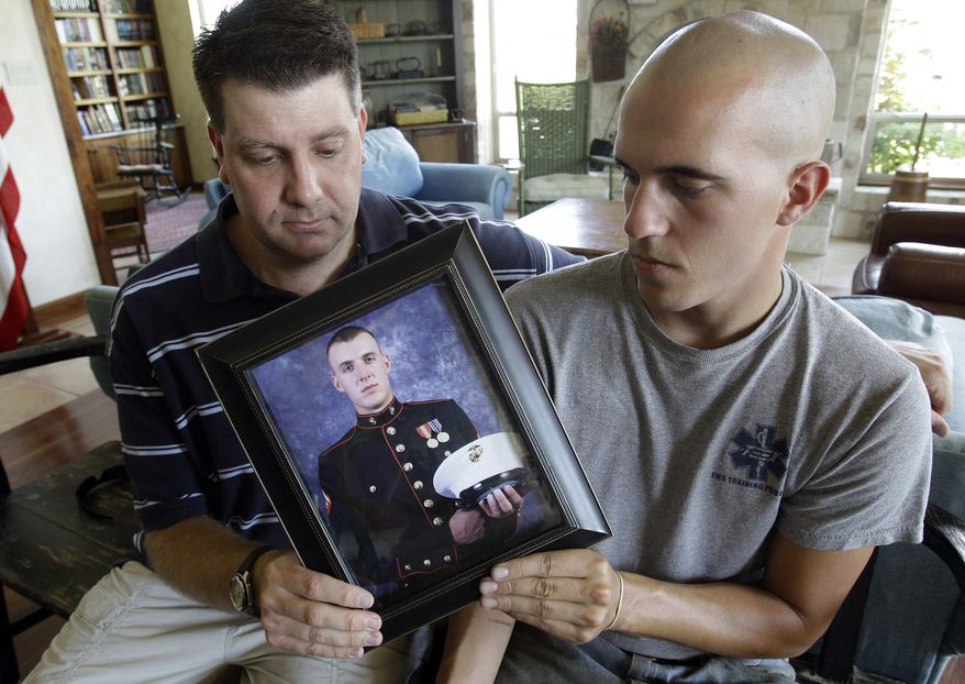 Jonathan Leicht, left, and Jesse Leicht, right, pose with a photo of their brother, Marine Cpl. Jacob Leicht, Saturday, May 29, 2010, in Kerrville, Texas. Cpl. Jacob Leicht, 24, was killed while on patrol in Afghanistan Thursday, May 27, 2010, making him the 1000th U.S. serviceman killed in the Afghan conflict. (AP Photo/Eric Gay)