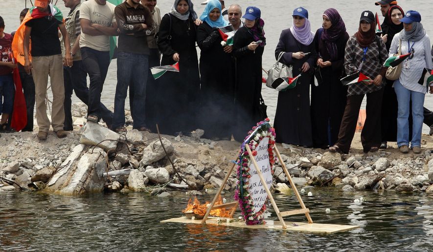 Palestinians look at a floating memorial sign at the port in Gaza City, Gaza Strip, on Tuesday, June 1, 2010, during a protest against the Israeli naval commando raid on a flotilla attempting to break the blockade of Gaza. (AP Photo/Hatem Moussa)