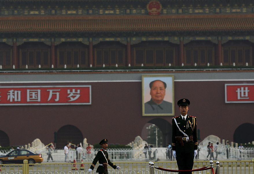 With a backdrop of a portrait of China's late communist leader Mao Zedong, center, a Chinese paramilitary policeman, right, stands still while another yawns while marching, in Tiananmen Square in Beijing on Friday, June 4, 2010. Chinese authorities tightened security on the vast square during the anniversary of the deadly 1989 crackdown on pro-democracy protestors, which was marked Friday. (AP Photo/Muhammed Muheisen)