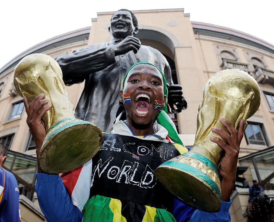 GLOBAL GOAL: A South African supporter holds copies of the World Cup trophy at Nelson Mandela Square in Johannesburg on Thursday. “Nelson Mandela, the world's great humanist and charismatic leader, was the person who got the World Cup for South Africa," said Sepp Blatter, president of soccer's world governing body.