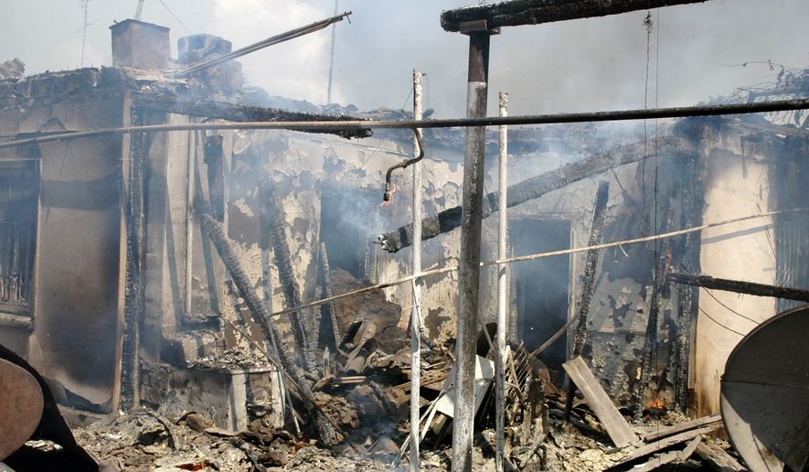 A burned-out Uzbek residence smolders after being torched by Kyrgyz men in Jalal-Abad, Kyrgyzstan, on Sunday, June 13, 2010. Thousands of Kyrgyz men brandishing sticks, metals bars and hunting rifles gathered at the city's horse-racing track and marched out to burn Uzbek property while frightened police stayed away. (AP Photo/Zarip Toroyev)