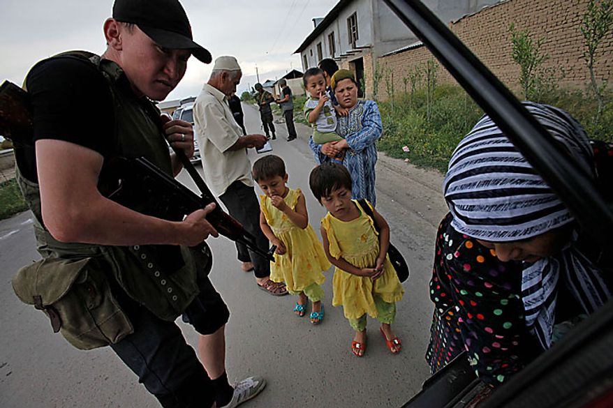 A Kyrgyz Army volunteer checks the trunk of passing car during a search for weapons as an ethnic Uzbek family look on at a checkpoint on the Uzbek side of the border near Osh, Kyrgyzstan, on Wednesday, June 16, 2010. Heavy arms fire rang out over Osh before dawn Wednesday as authorities struggled to bring order to the country's south, which has been thrust into chaos by days of deadly ethnic riots. The violence has prompted more than 100,000 Uzbeks to flee for their lives to Uzbekistan, with tens of thousands more camped on the Kyrgyz side or stranded in a no man's land. (AP Photo/Alexander Zemlianichenko)
