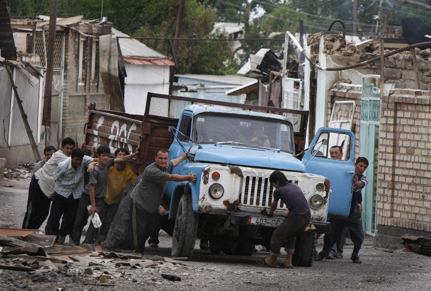Ethnic Uzbek men push a truck as they build a barricade in the Uzbek district in the southern Kyrgyz city of Osh on Thursday, June 17, 2010. Some 400,000 people have been displaced by ethnic violence in southern Kyrgyzstan, the United Nations announced Thursday, dramatically increasing the official estimate of a refugee crisis that has left throngs of desperate, fearful people without enough food and water in grim camps along the Kyrgyz-Uzbek border. (AP Photo/Sergei Grits)