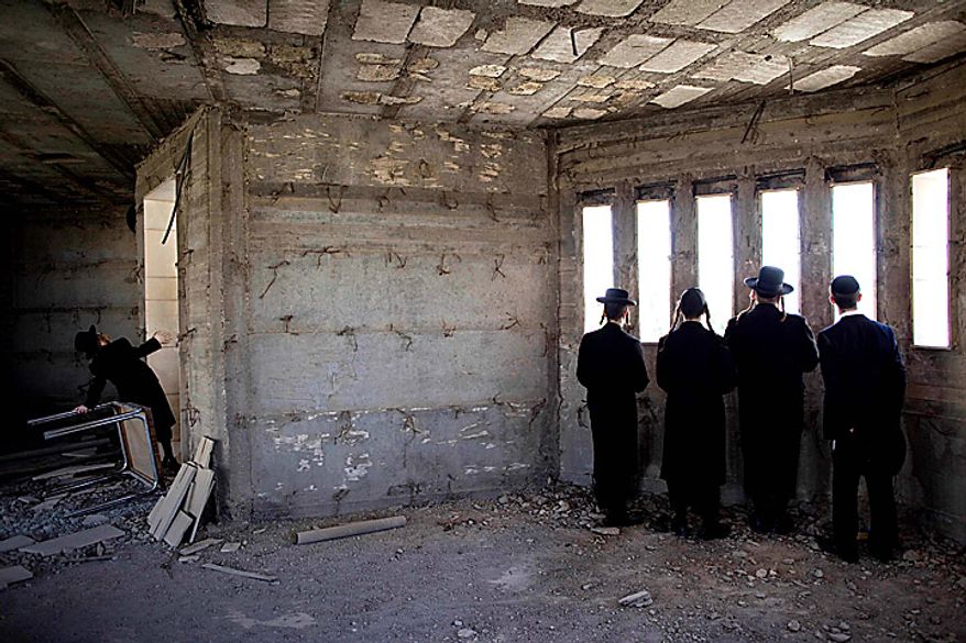 Ultra-Orthodox Jewish men in Jerusalem watch, through the windows of a building under construction, a mass demonstration against an Israeli Supreme Court ruling forcing the integration of a religious girls school on Thursday, June 17, 2010. Police said about 100,000 people converged in downtown Jerusalem to support the parents who oppose integration and are to be jailed for two weeks for defying the integration efforts by keeping their daughters from school. (AP Photo/Oded Balilty)