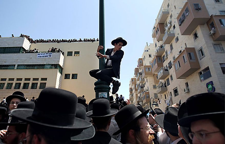 An Ultra-Orthodox Jewish man climbs on a pole in Bnei Brak, Israel, on Thursday, June 17, 2010, during a demonstration against an Israeli Supreme Court ruling forcing the integration of a religious girls school. Tens of thousands demonstrated in Bnei Brak, and an even bigger protest took place in Jerusalem. (AP Photo/Ariel Schalit)