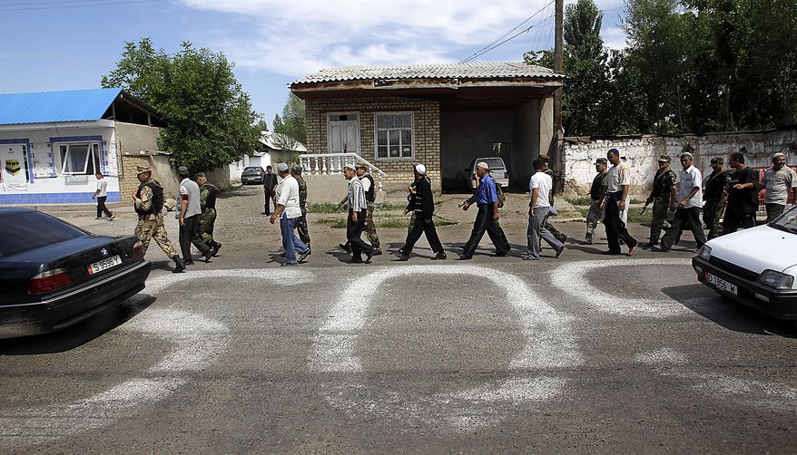 Kyrgyz and ethnic Uzbek men walk along an SOS sign on the street of Suzak, the Uzbek neighborhood near the southern Kyrgyz city of Jalal-Abad, Kyrgyzstan, Friday, June 18, 2010, as they perform joint Kyrgyz-Uzbek patrol. Some 400,000 people have been displaced by ethnic violence in southern Kyrgyzstan, the United Nations announced Thursday, dramatically increasing the official estimate of a crisis that has left throngs of desperate, fearful refugees without enough food and water in grim camps along the Uzbek border. (AP Photo/Sergey Ponomarev)