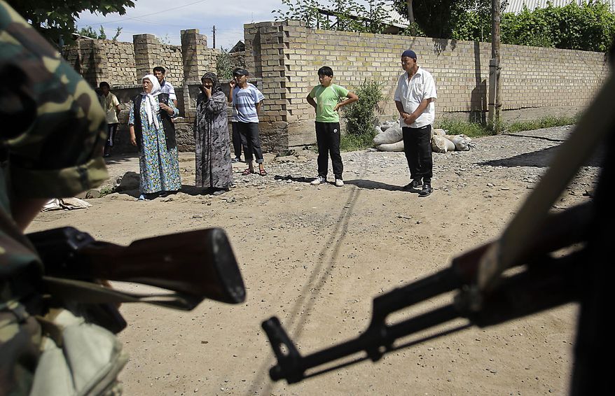 Ethnic Uzbek people watch the joint Kyrgyz-Uzbek patrol walking along a street of Suzak, in the Uzbek neighborhood near the southern Kyrgyz city of Jalal-Abad, Kyrgyzstan, Friday, June 18, 2010. Some 400,000 people have been displaced by ethnic violence in southern Kyrgyzstan, the United Nations announced Thursday, dramatically increasing the official estimate of a crisis that has left throngs of desperate, fearful refugees without enough food and water in grim camps along the Uzbek border. (AP Photo/Sergey Ponomarev)
