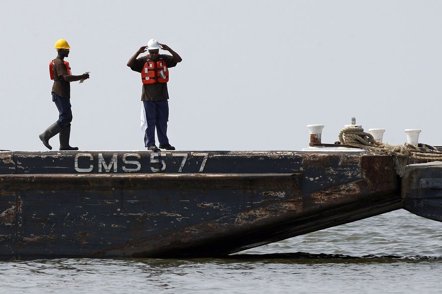 Workers walk along a line of barges anchored in Pass Abel on the coast of Louisiana near Grand Isle, La., Monday, June 21, 2010. When completed, the barges, which will be lined up end-to-end, are expected to serve as a barrier against oil from the Deepwater Horizon oil spill from entering Barataria Bay. (AP Photo/Patrick Semansky)