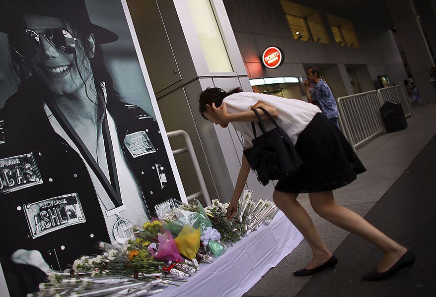 ** FILE ** A woman lays flowers at a makeshift memorial place ahead of the first death anniversary of King of Pop Michael Jackson in Tokyo, Friday, June 25, 2010. (AP Photo/Junji Kurokawa)