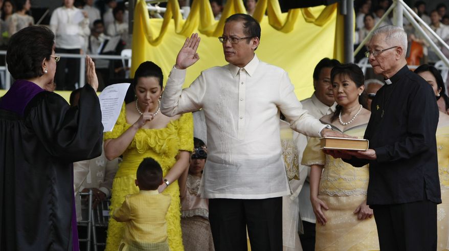 President Benigno Aquino III, center, takes his oath before Supreme Court Associated Justice Conchita Carpio-Morales as the Philippines' 15th President during inaugural ceremony Wednesday June 30, 2010, in Manila, Philippines. Mr. Aquino, the only son of Philippine democracy icons, the late President Corazon Aquino and assassinated opposition leader Sen. Benigno Aquino Jr., won by a landslide in the May 10 automated presidential elections. At right holding the Holy Bible is Jesuit priest Father Catalino Arevalo. (AP Photo/Bullit Marquez)