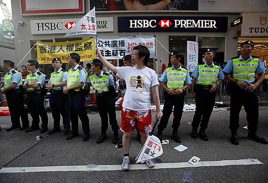 A pro-democracy protester waves a flag that reads "Unneeded king of the king (meaning Chinese government)" during a demonstration in Hong Kong on Thursday, July 1, 2010. Hecklers besieged Hong Kong's Democrats at the opposition camp's flagship protest march on Thursday, accusing them of selling out their cause by striking a deal with Beijing on conservative electoral changes in the semiautonomous Chinese territory. (AP Photo/Kin Cheung)